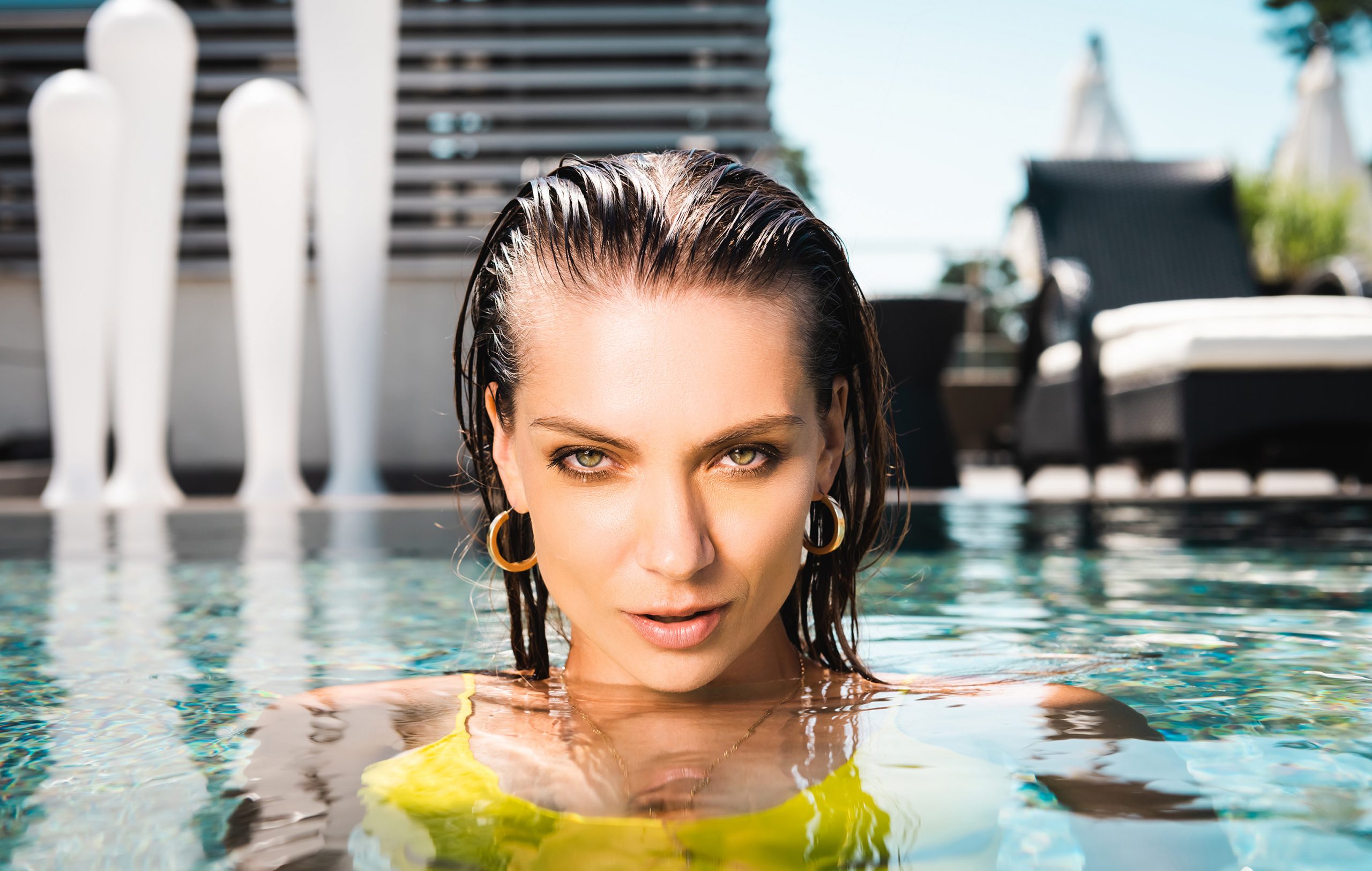 beautiful sexy woman looking at camera in swimming pool on resort